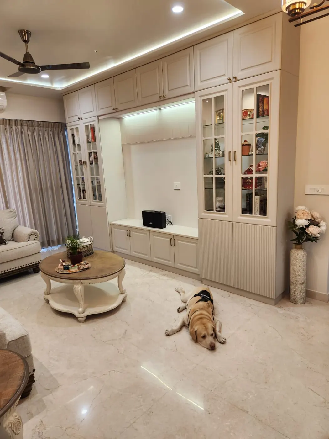 Full-wall TV unit with storage and display shelves under a false ceiling, Pune