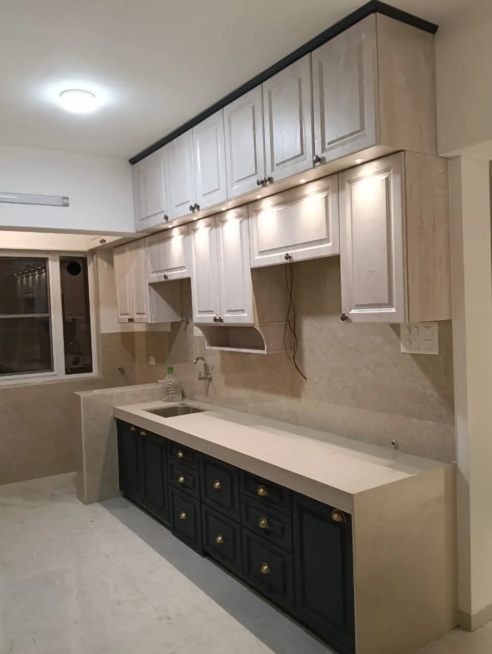 Navy and beige shaker-style modular kitchen with under-cabinet lighting by Bella Kitchens, Pune